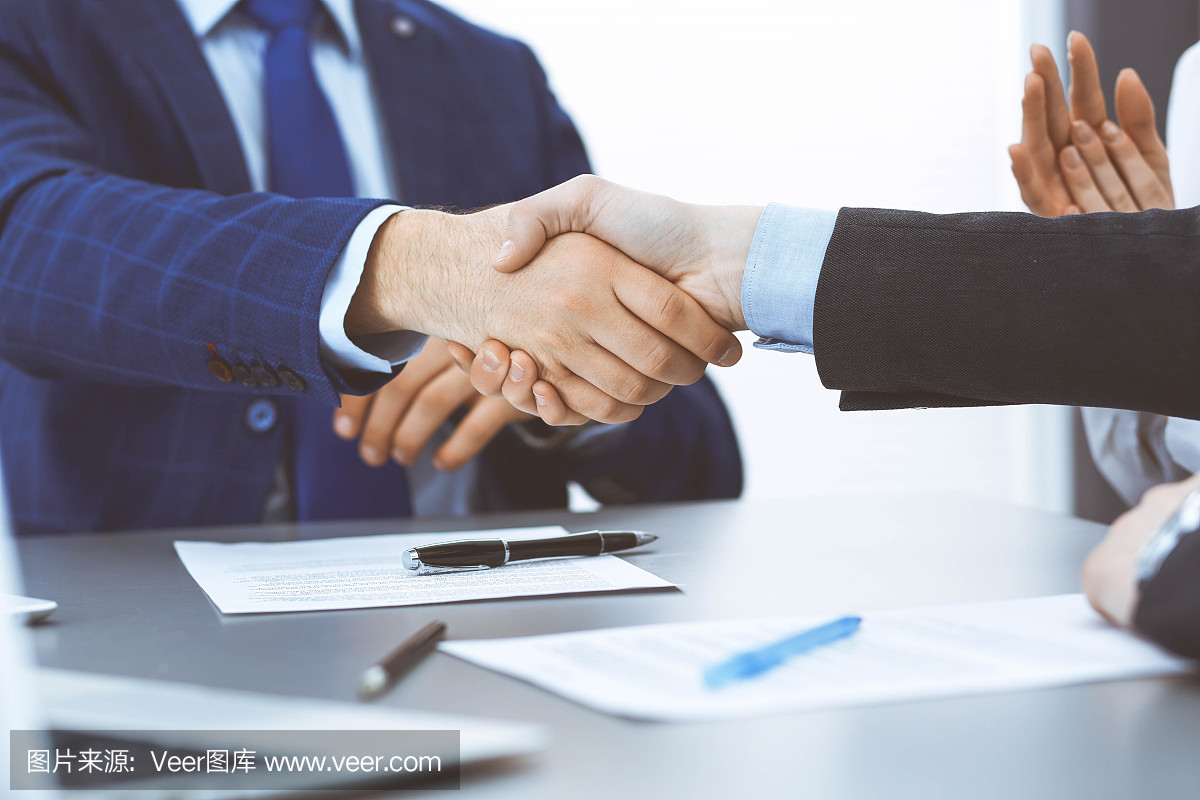 商人们握手,完成一份文件签名。会议、合同及律师咨询理念